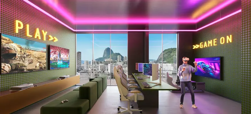 Sala gamer do First Humaitá com estações de jogos e vista para o Pão de Açúcar