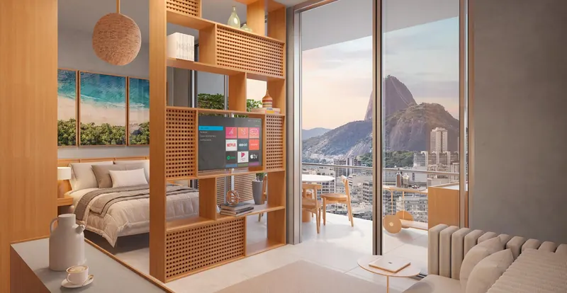Studio decorado do First Humaitá com estante vazada e vista para o Pão de Açúcar